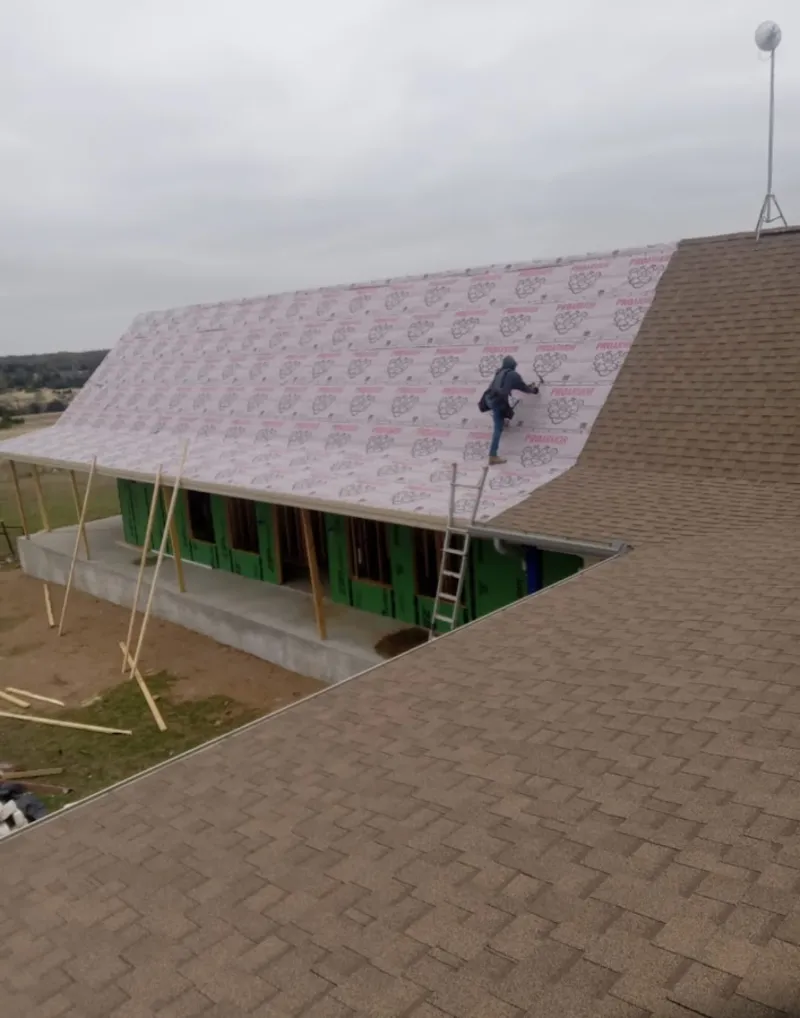 Worker preparing underlayment for a metal roof installation in Porter